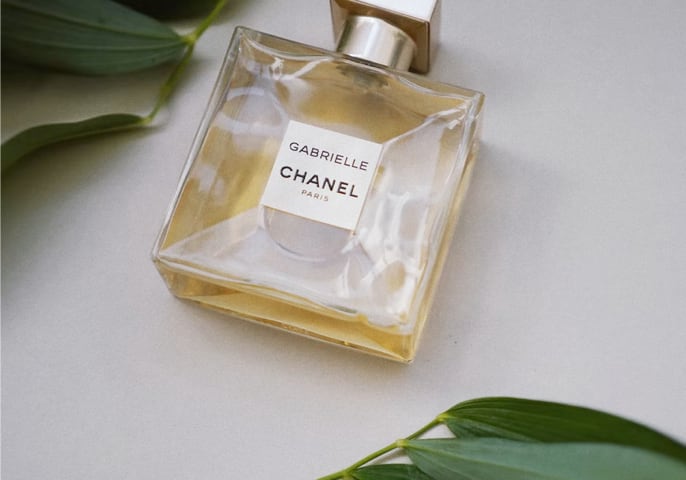 Chanel perfume laid out in a table with leaves besides it.